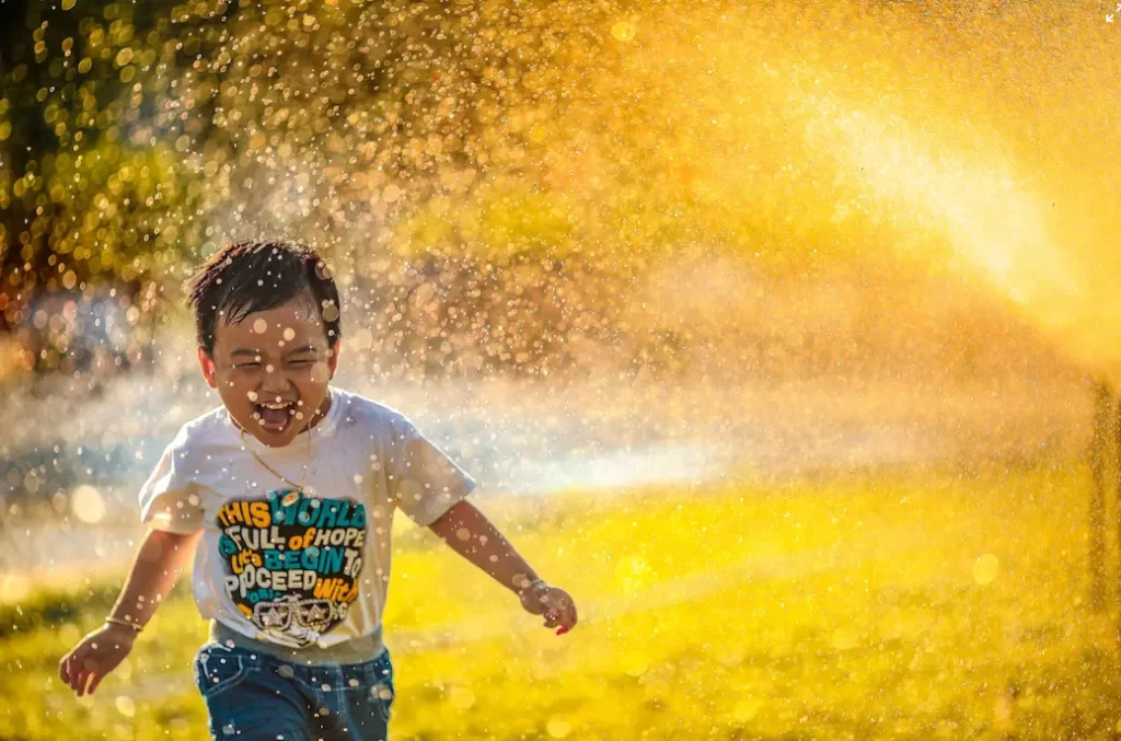 happy child playing in water sprinkler