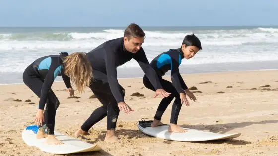father teaching kids to surf