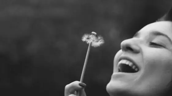woman blowing dandelion seeds